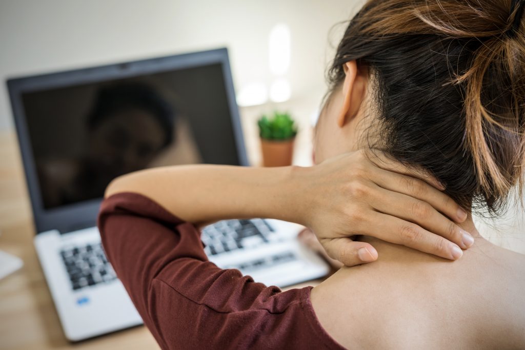 女人在办公桌上用笔记本电脑工作时按摩脖子