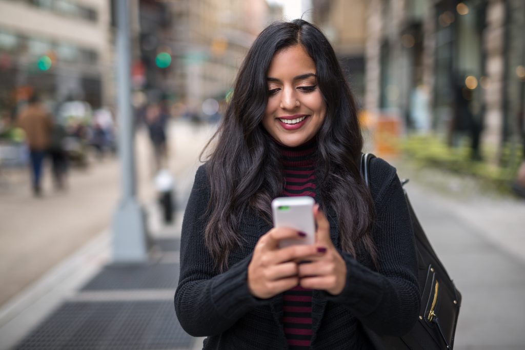 一名女子在公共场合使用智能手机时微笑