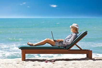 女子在海滩度假时使用笔记本电脑