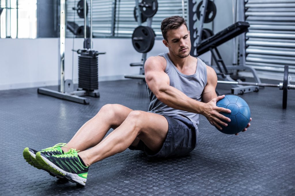 man exercising at gym with medicine ball