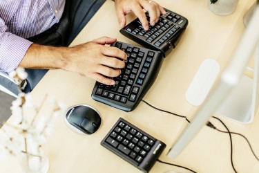 man at desk using ergonomic keyboard, mouse and numeric pad
