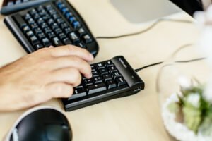 一名男子在数字键盘上打字，桌面上有Goldtouch键盘和鼠标manbetx万博app下载